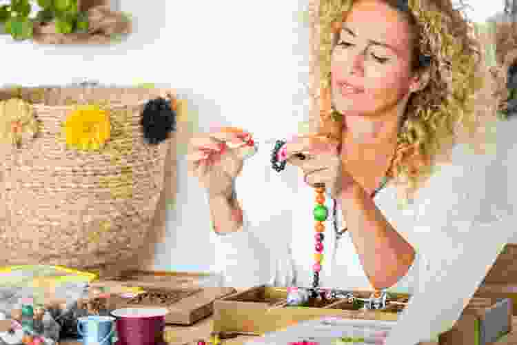 woman stringing beads together into a necklace