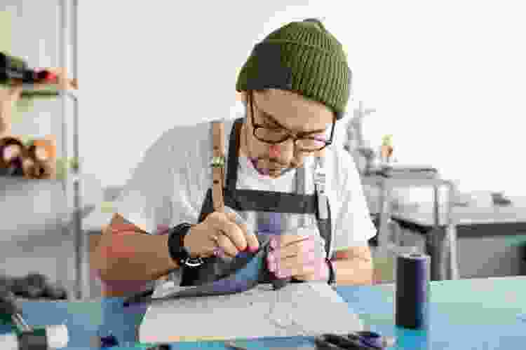 man sewing fabric in studio