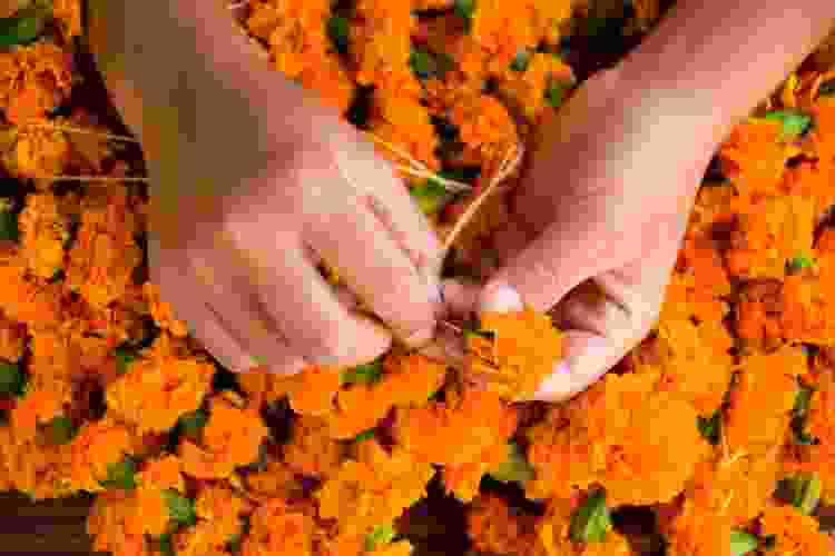 hands making garland out of marigolds