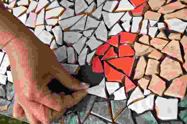 hand placing tiles in mosaic