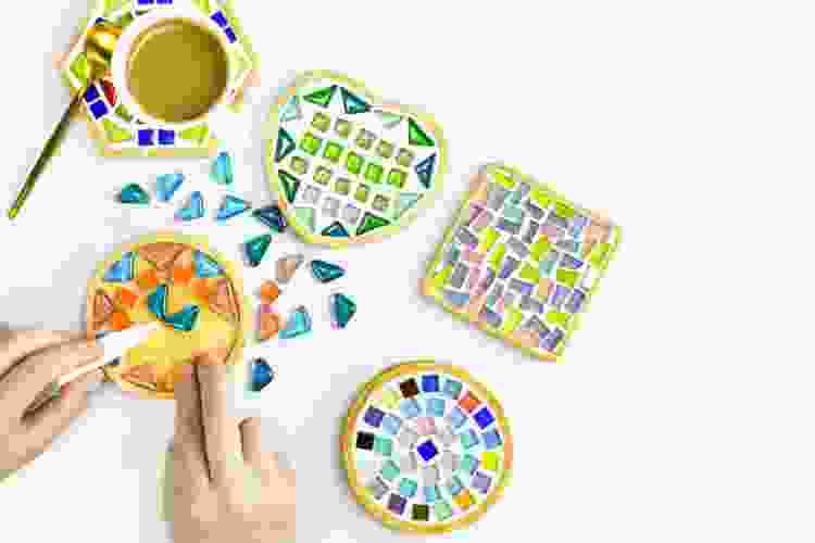 hand placing small tiles into mosaic art piece