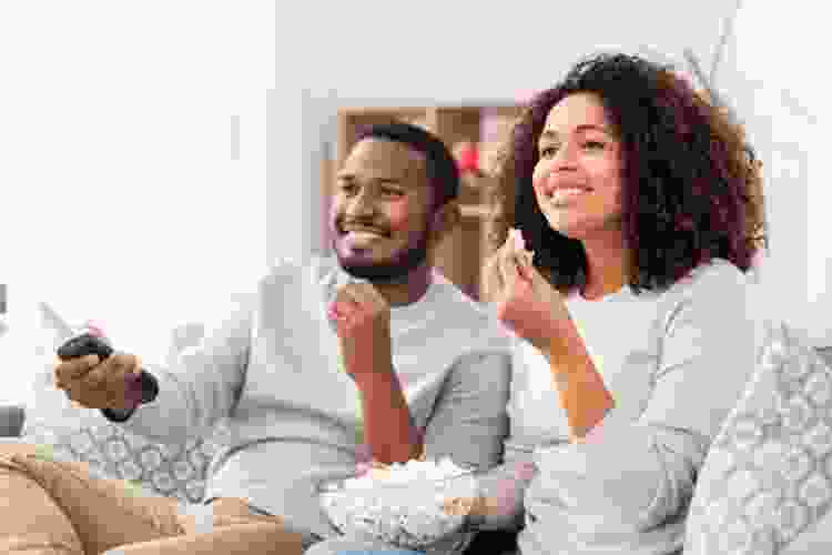 couple watching tv with popcorn on the couch