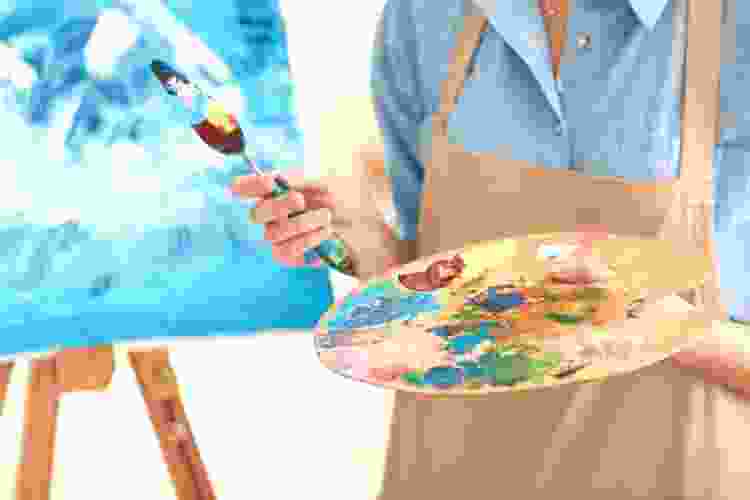 blue canvas on easel and artist holding palette