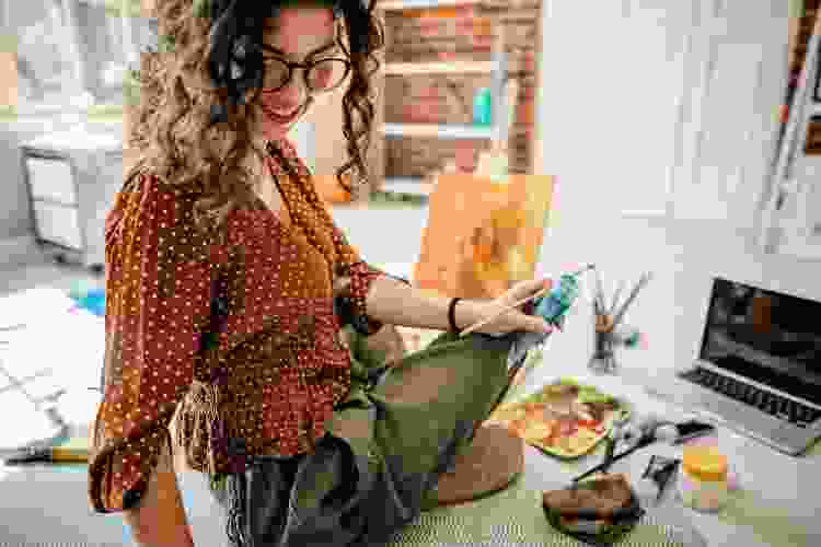 young woman with laptop painting at home