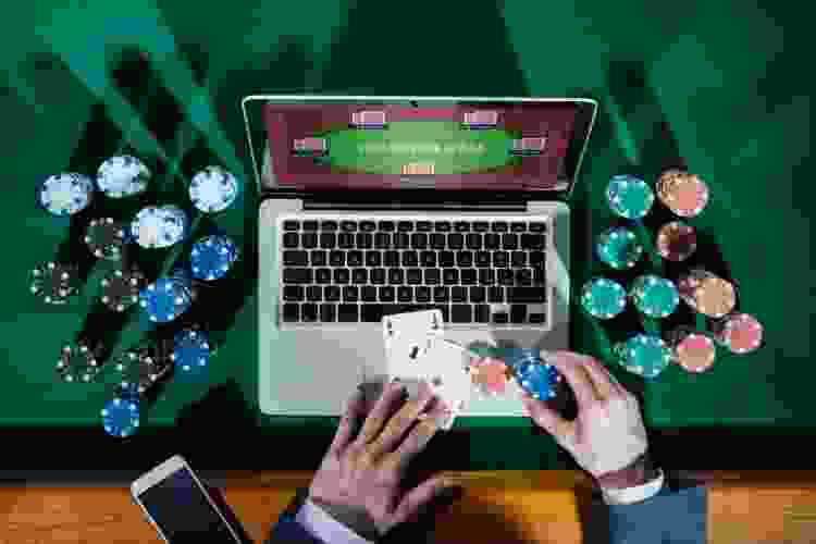 person playing Texas hold'em on laptop surrounded by poker chips