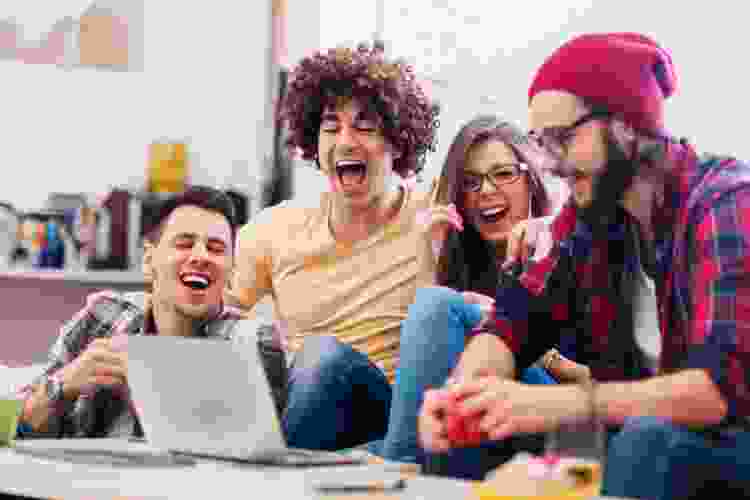 group of friends laughing at laptop