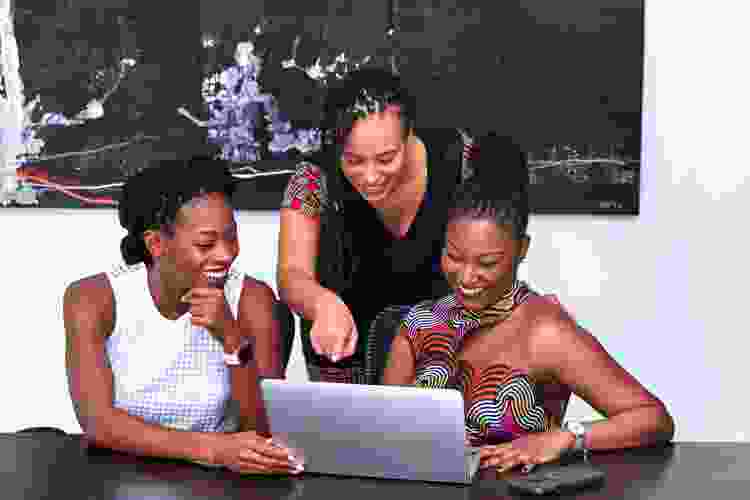 three women playing trivia games on laptop