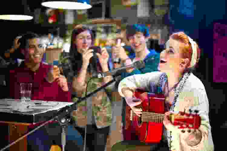 young woman playing guitar and singing on stage