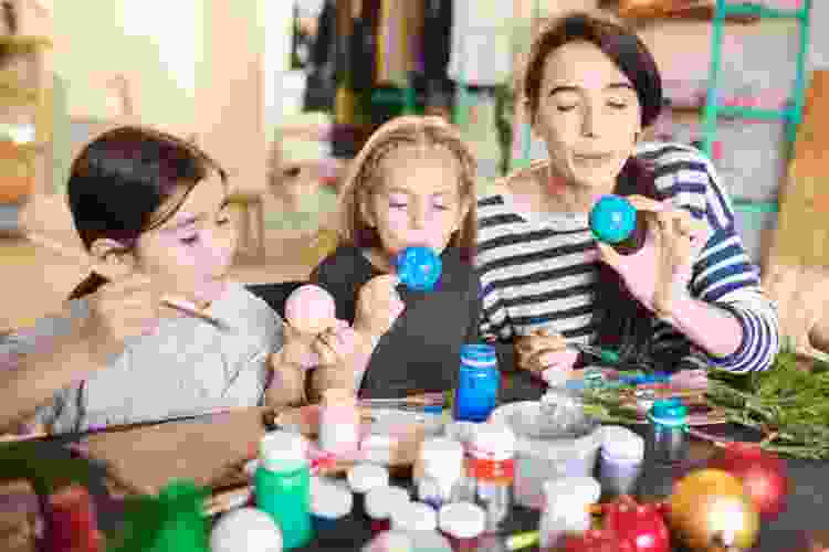 mother and two young children painting handmade Christmas ornaments together