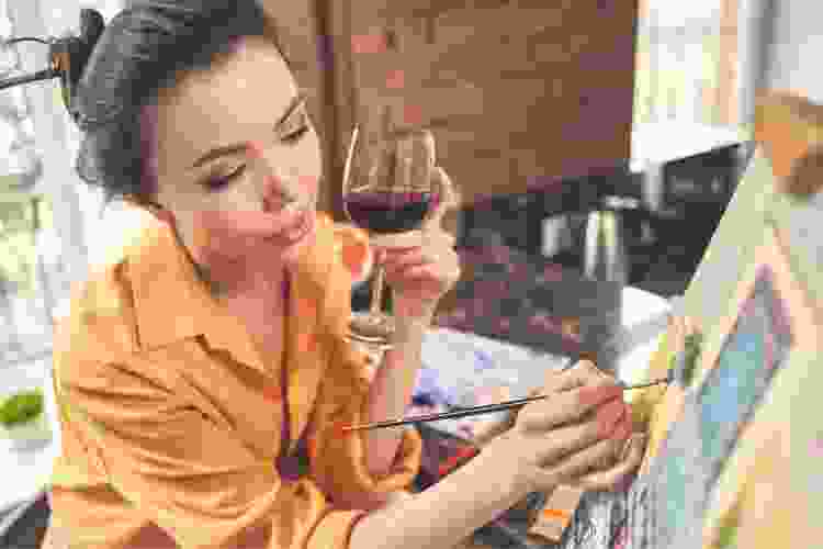 woman drinking wine and painting on canvas