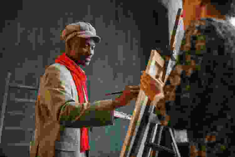 young man painting art on canvas and easel