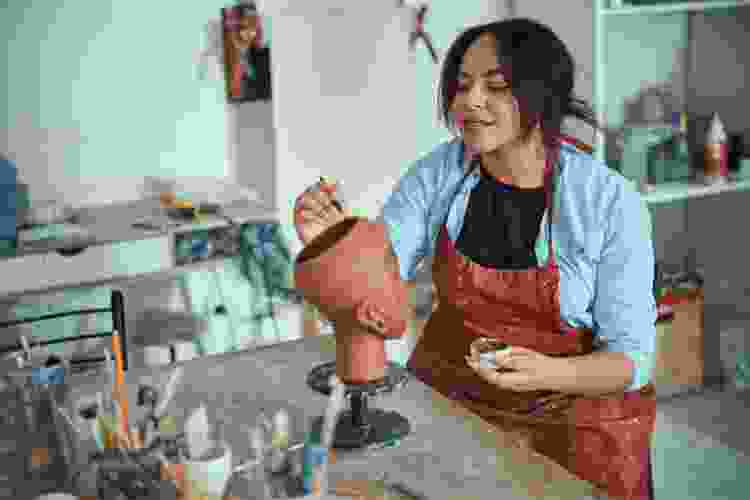 woman in studio painting on clay sculpture