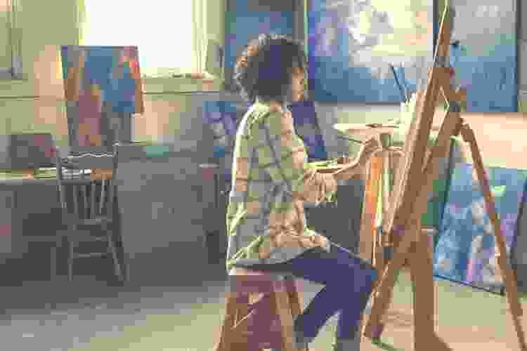 woman painting on canvas in dim room