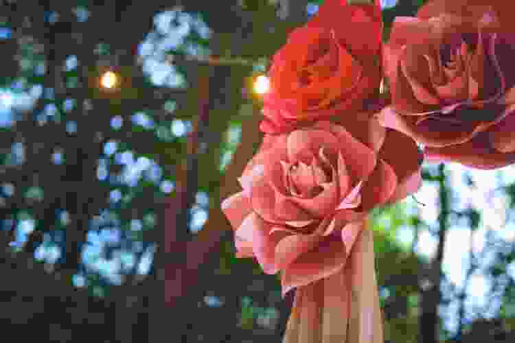 paper flowers hanging from string lights in the garden