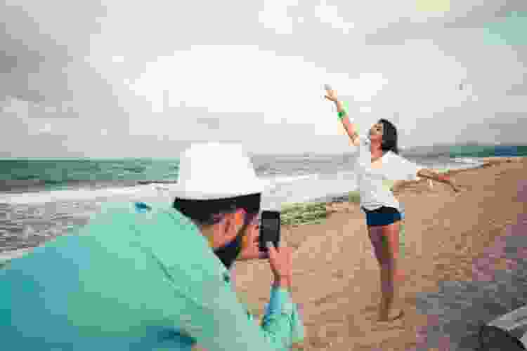 husband taking photos of his wife on the beach