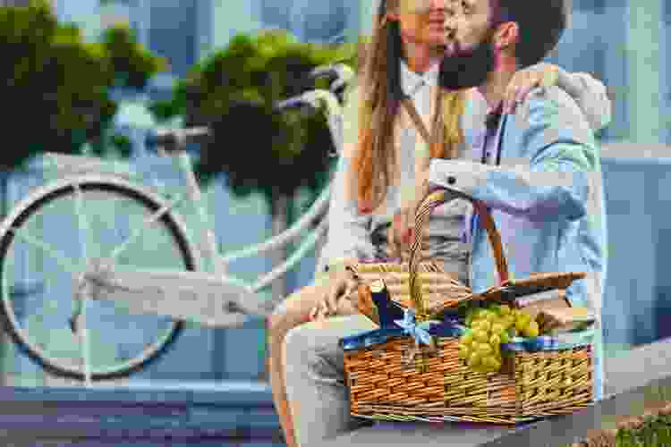 couple sitting on a bench together with a picnic basket