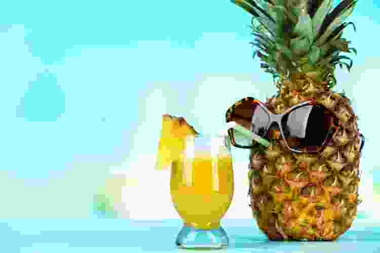 pineapple wearing sunglasses and drinking a pineapple cocktail from a straw