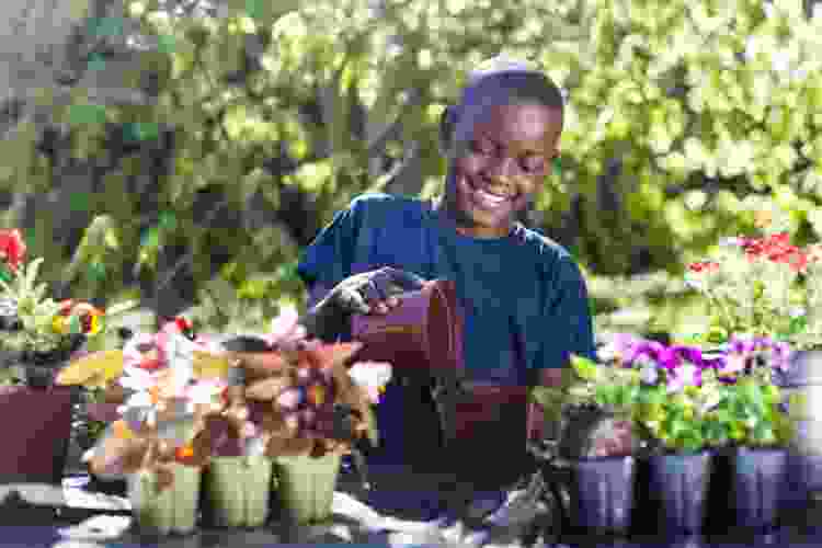 young boy planting flowers into pots