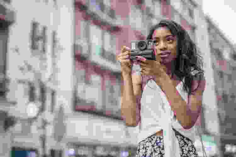 woman in street holding polaroid camera