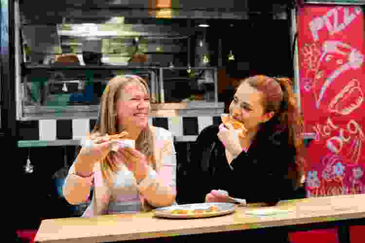 women eating pizza by food truck