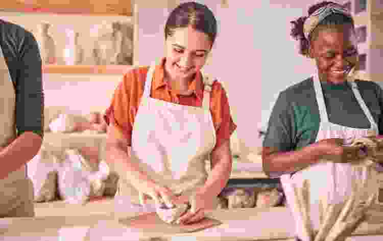 group of friends molding clay in pottery class