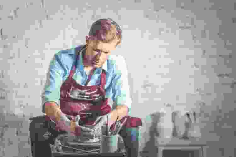 man molding clay on pottery wheel