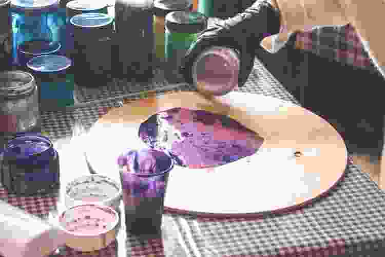 pouring purple paint on wooden board