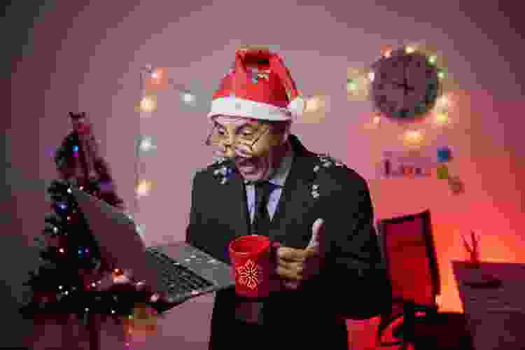 man in Santa hat holding laptop