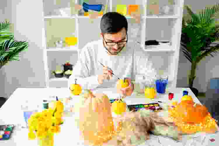 man painting pumpkins at home