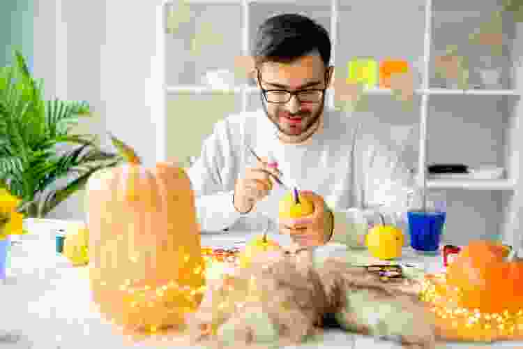 guy painting pumpkins at fall party