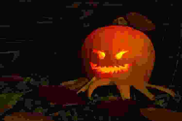 Jack-o-lantern with spider legs carved into the bottom