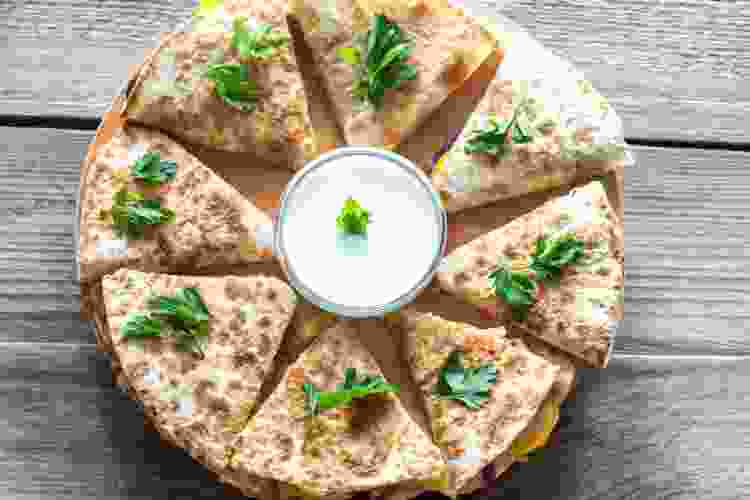 triangle cut quesadillas surrounding bowl of sour cream