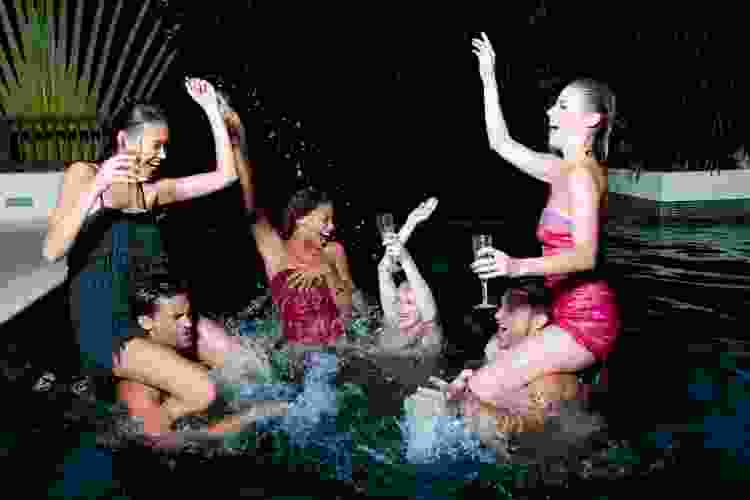 friends dancing in a swimming pool at night