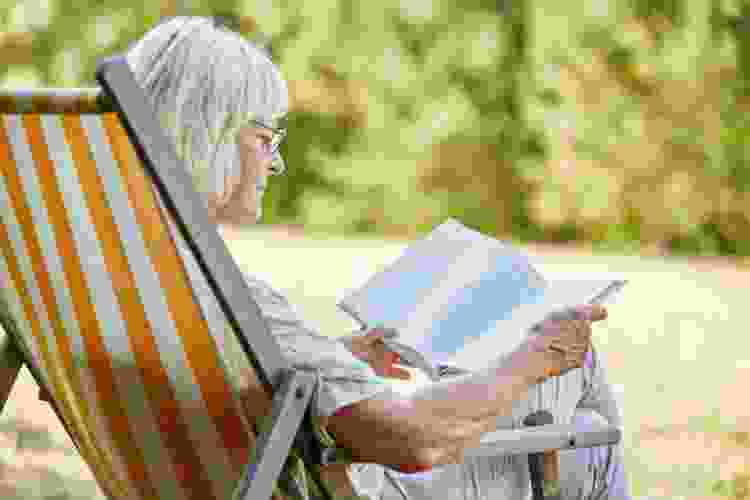 grandmother reading book outside in lawn chair