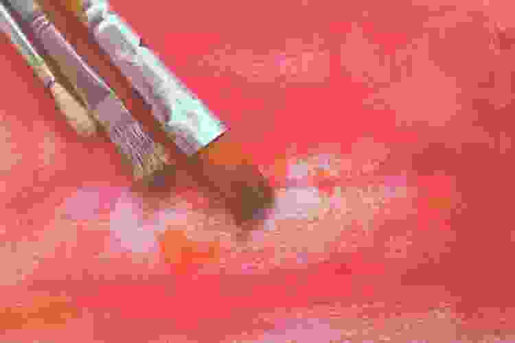 paint brush on canvas of red paint