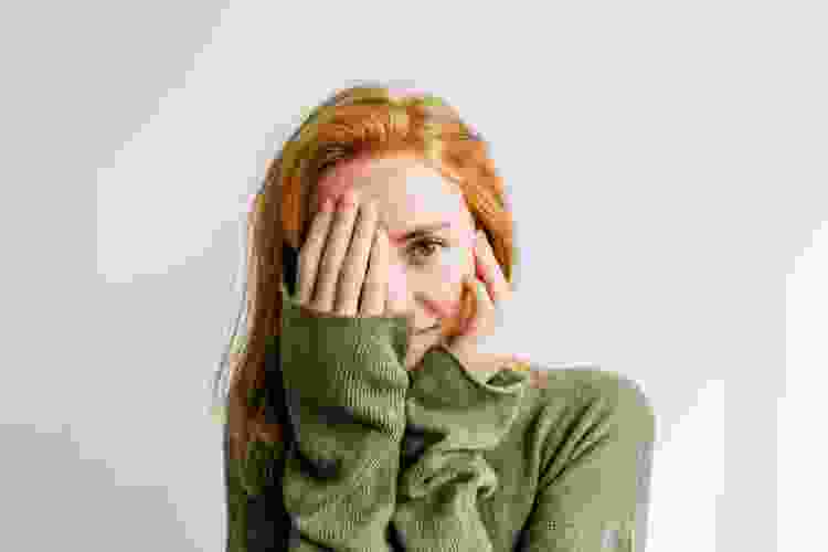 Red-haired woman looking at the camera covering an eye