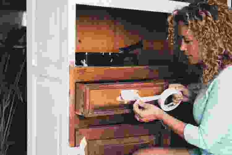 woman taping old dresser before adding fresh coat of paint