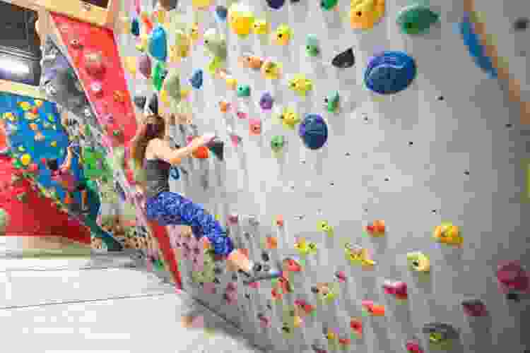 young woman climbing indoor rock wall