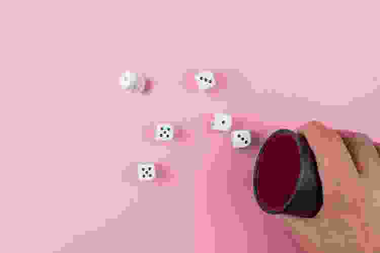 rolling dice on pink table