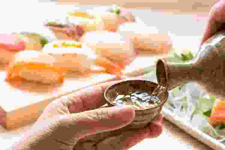 pouring sake into cup on a table of sushi