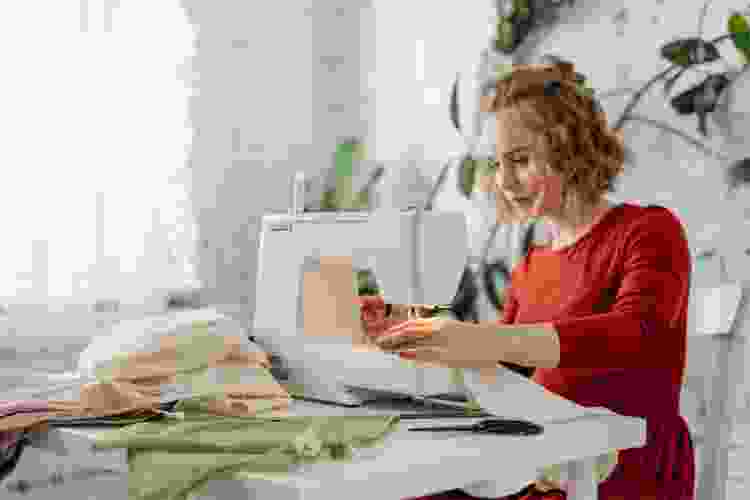 young woman with fabric on sewing machine