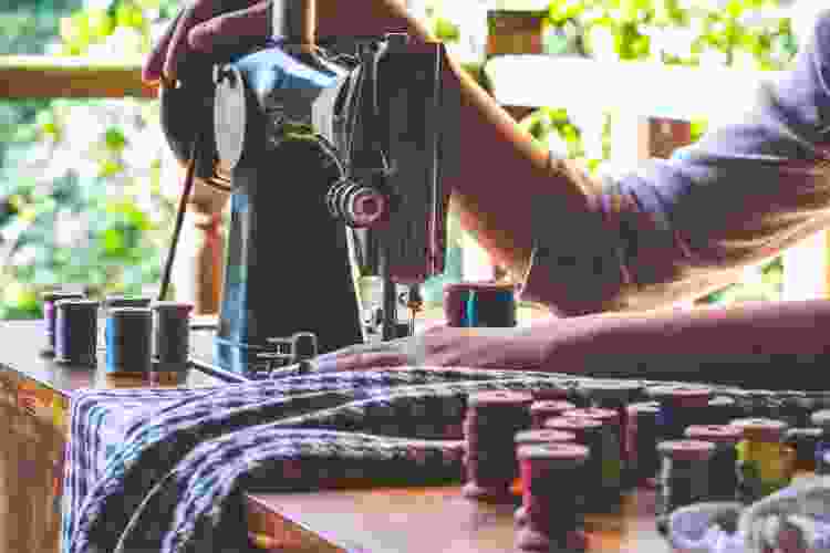 hands pushing fabric through sewing machine