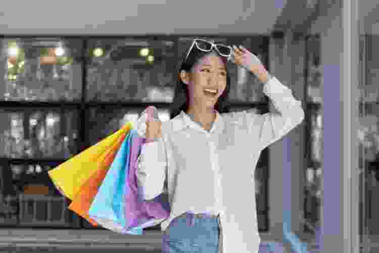 woman walking out of store with an armful of shopping bags