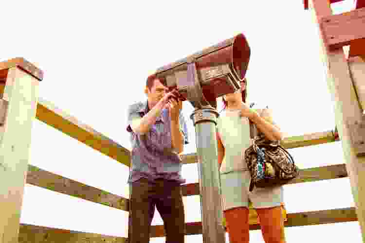 couple sightseeing through telescope