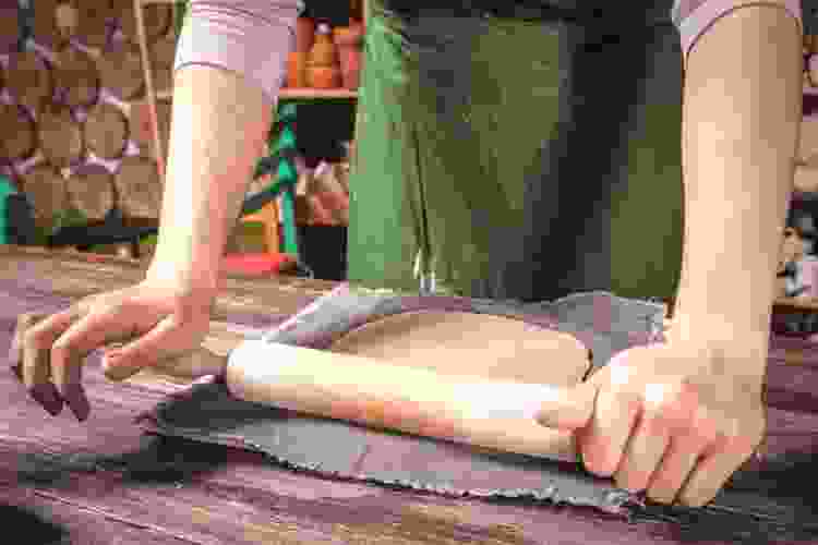 hands rolling clay with rolling pin