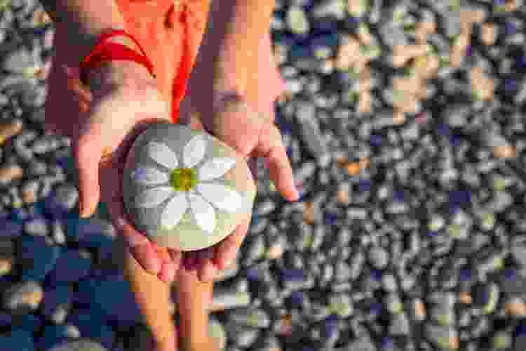 river stone with painting of a white daisy on it