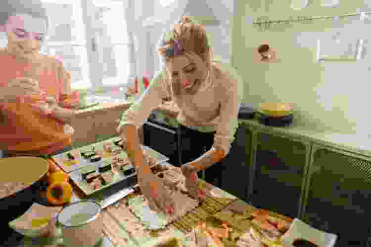 two friends rolling sushi in the kitchen at home