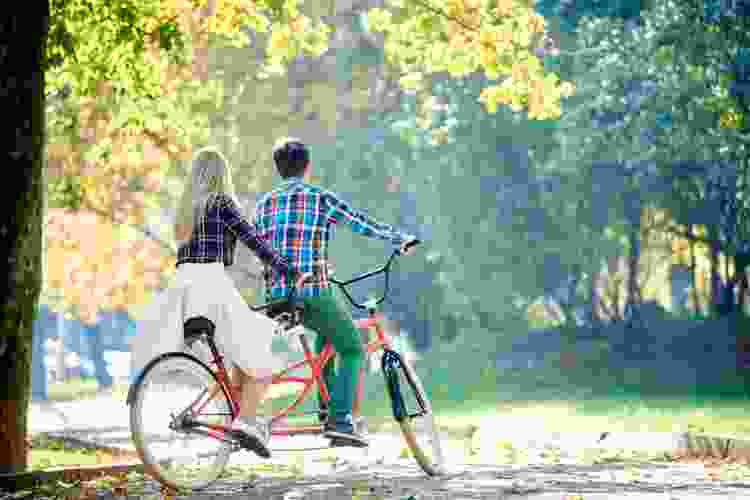 couple riding tandem bike through the park