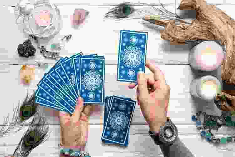 hands holding blue deck of tarot cards