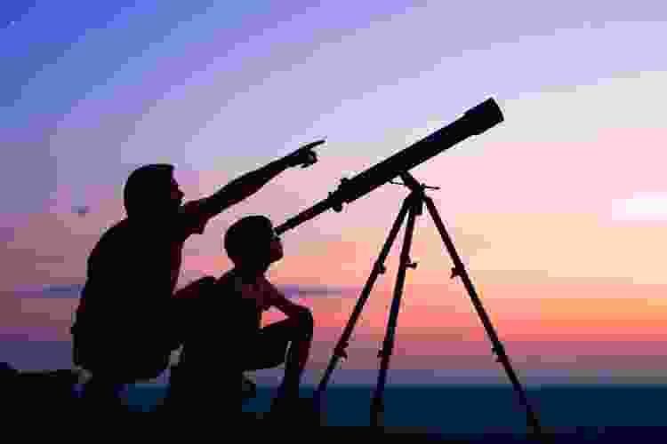 father and son looking at sky through telescope